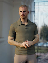 Man wearing a green polo shirt standing outdoors with blurred background